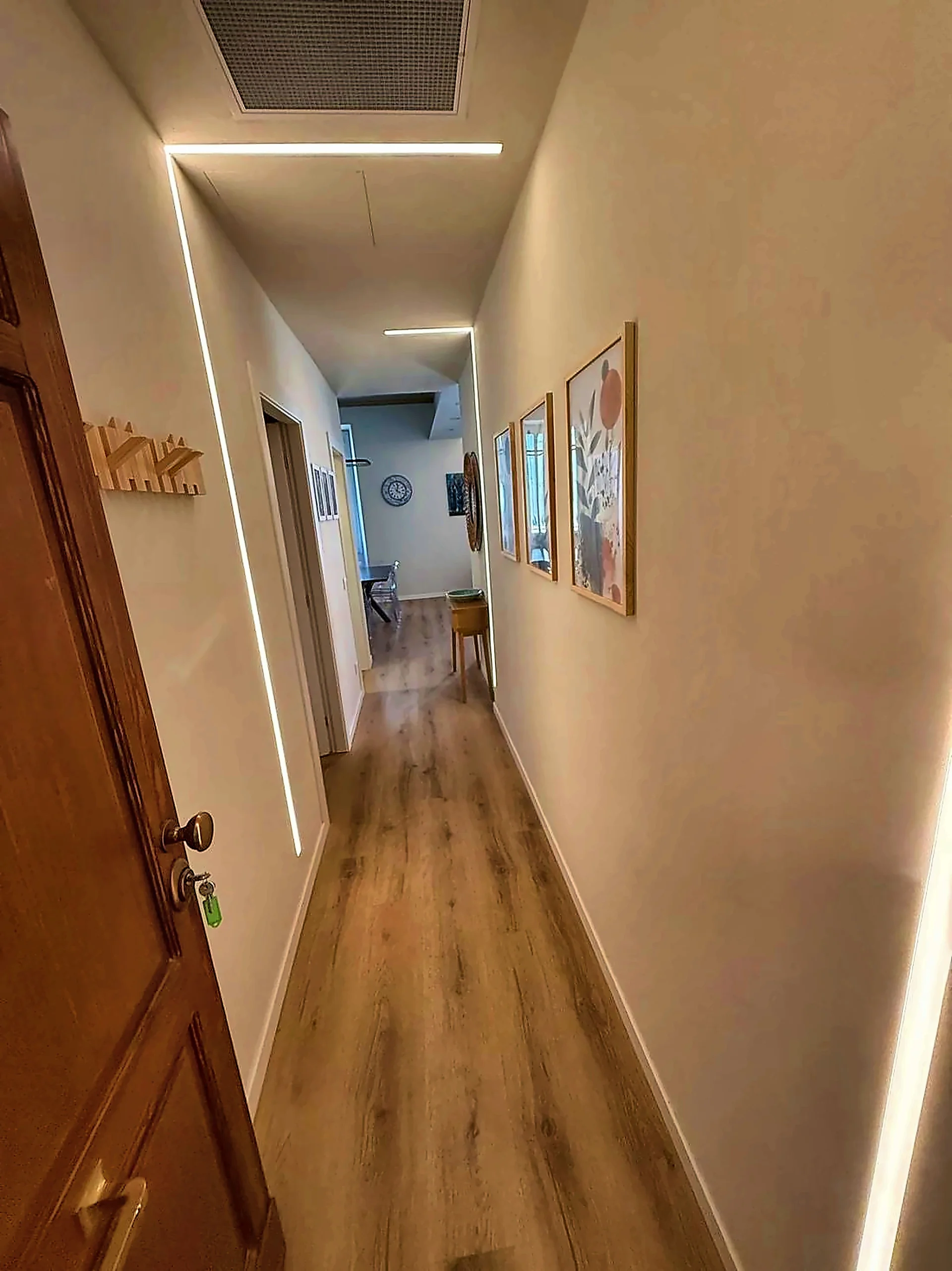 Corridoio ristrutturato con illuminazione lineare e parquet